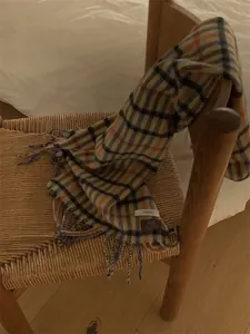 Macro detail of the vintage plaid wool scarf with long fringe and brand label on a chair
