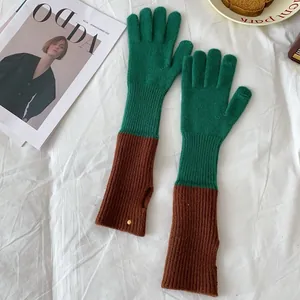 Detail of color-block knit gloves in forest green and brown with ribbed texture