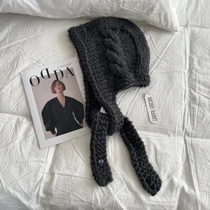 Detail of chunky knit dark grey balaclava hat with cable stitch pattern and heart charm