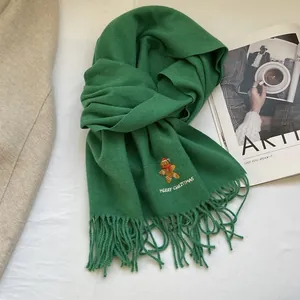 Detail of dark green Christmas scarf with gingerbread embroidery and fringe edges