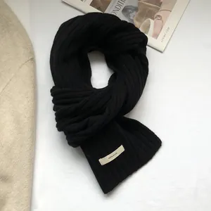 Detailed texture of a black 100% wool knit scarf featuring thick ribbed pattern design
