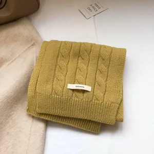 Detailed knit texture of 100% pure wool scarf in yellow with authentic fabric label