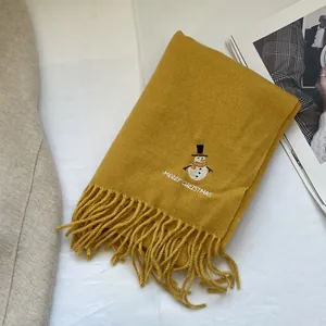 Detail of ginger yellow scarf with snowman embroidery and Merry Christmas text