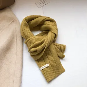 Macro shot of 100% wool ginger yellow cable knit scarf showing texture and material label
