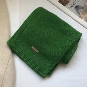 Detail of 100% Australian wool scarf featuring emerald green knit and leather label