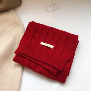 Detailed texture of red cable knit 100% wool scarf with white authentic wool label