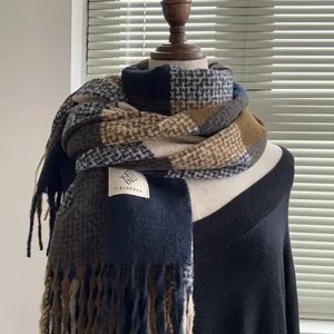 Detail of blue and brown plaid scarf featuring soft cashmere-like texture and fringed edges