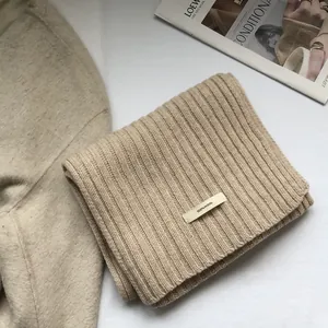 Detailed macro view of 100% wool beige ribbed scarf with quality fabric tag and texture