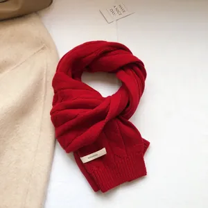 Detailed knit texture of a dark red 100% wool scarf with classic cable stitch patterns
