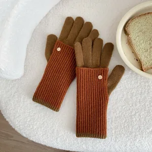 Detail of burnt orange and brown knit gloves with ribbed texture and gold metal buckle