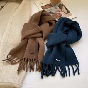 Close-up of soft 100% wool knit scarves with tassel edges and small metal plates