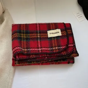 Détail d'une écharpe à carreaux rouge et noir effet cachemire avec des bords surjetés noirs