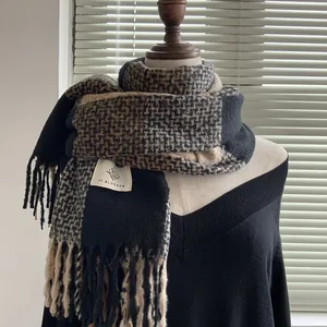 Close-up of thick plaid scarf texture with fringes on a black sweater mannequin