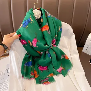 Détail d'une écharpe en coton et lin vert foncé avec motif chien cartoon coloré et franges