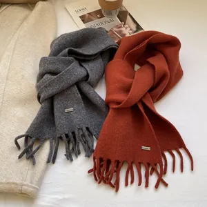 Detailed macro of 100% wool knitted scarves with tassels and metallic logo plates