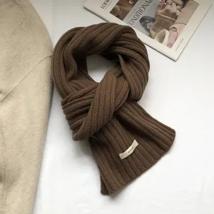 Detail of 100% wool knit scarf featuring thick rib texture and white fabric care label