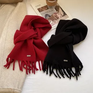 Detail shot of black and red 100% wool scarves with soft fringe and metal labels