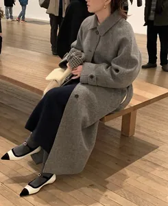 Classic grey wool blend long coat with notch lapels shown in an elegant gallery setting