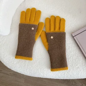 Detail of two-tone knit gloves featuring ribbed texture and a golden metal decorative button