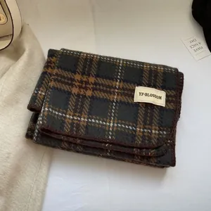 Détail d'une écharpe à carreaux gris effet cachemire avec étiquette et bord surjeté
