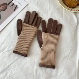 Detail of winter knit gloves with color-block design and golden metal button accent