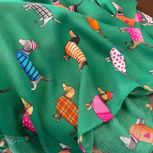 Gros plan d'une écharpe en coton vert avec motifs de teckels rigolos et détails de franges