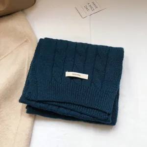 Macro detail of dark green 100% wool scarf featuring a classic chunky cable knit pattern