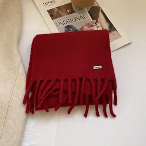Detailed texture of dark red 100% wool scarf with fringe and silver Fashion metal tag