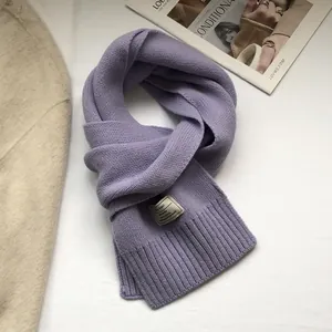Macro view of purple knitted wool scarf showing rib knit texture and decorative label