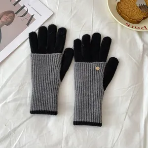 Close-up of black and grey knit gloves featuring a gold decorative button on the wrist