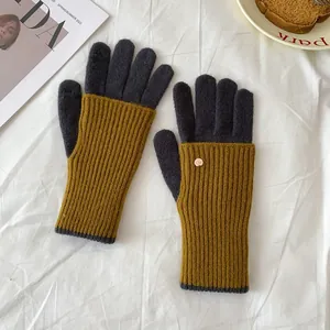 Detail of knit gloves with gold metal logo on a cozy winter lifestyle background