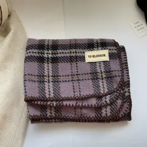 Détail d'un châle à carreaux violets façon cachemire avec étiquette de marque