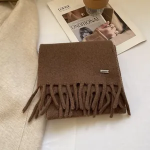 Close-up of dark brown 100% wool knitted scarf showing texture and metallic label