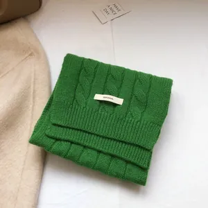Detail of 100% pure wool green scarf showing thick cable knit texture and high quality fiber