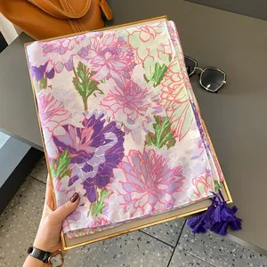 Eleganter Seidenschal mit Blumenmuster und lila Fransen in einem goldenen Tablett