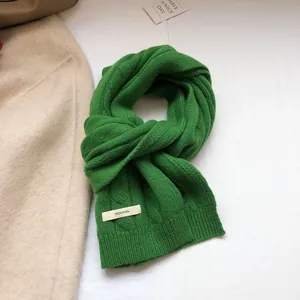 Detailed close-up of 100% Australian wool scarf featuring green cable knit and care label