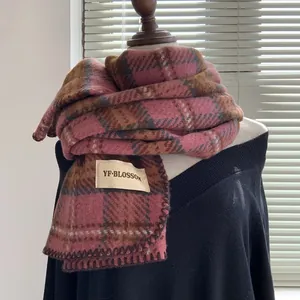 Gros plan d'une écharpe à carreaux rose et marron avec franges et étiquette de marque tissée