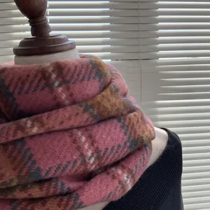 Gros plan d'une écharpe à carreaux rose et marron montrant la texture douce du faux cachemire