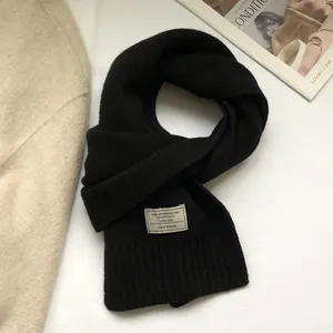 Detailed close-up of 100% Australian wool scarf featuring black rib knit and brand label