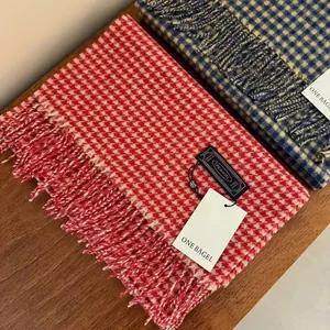 Detailed view of 100% wool red and white plaid scarf with decorative soft fringes