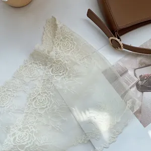 Detail of vintage white lace headscarf featuring 3D rose embroidery and scalloped edges