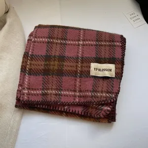 Détail d'une écharpe en cachemire à carreaux rose et marron avec texture épaisse et étiquette