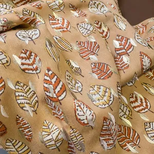 Dettaglio di sciarpa con motivo a foglie con accenti in lamina d'oro e trama twill