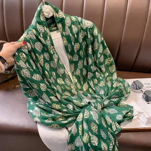 Dettaglio di sciarpa verde scuro con stampa foglia d'oro su leggero tessuto in cotone lino