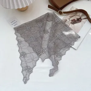 Flat lay of gray lace triangle scarf with floral embroidery and retro fashion props
