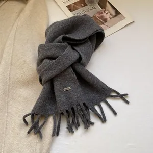 Close-up of handmade metal label and fringe on soft dark grey 100% wool scarf