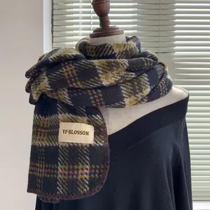 Détail macro de l'écharpe effet cachemire à carreaux colorés et son étiquette tissée de marque
