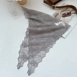 Detail shot of a grey lace headscarf with hollow floral patterns in a French chic style