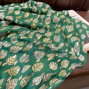 Dettaglio ravvicinato della sciarpa verde scuro con stampa foglia oro e trama