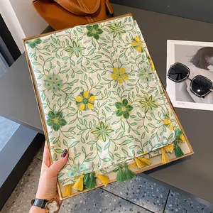 Sciarpa floreale in cotone e lino verde e gialla con nappe in un ambiente lifestyle